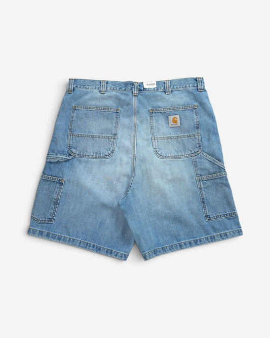 Блакитні джинсові шорти Carhartt WIP вільного крою, вигляд ззаду, з великими накладними кишенями, додатковими відділеннями для інструментів та фірмовим логотипом.
