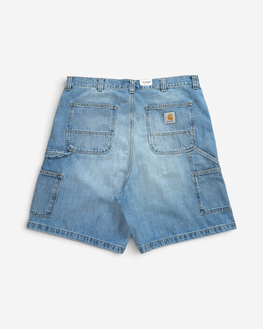Блакитні джинсові шорти Carhartt WIP вільного крою, вигляд ззаду, з великими накладними кишенями, додатковими відділеннями для інструментів та фірмовим логотипом.