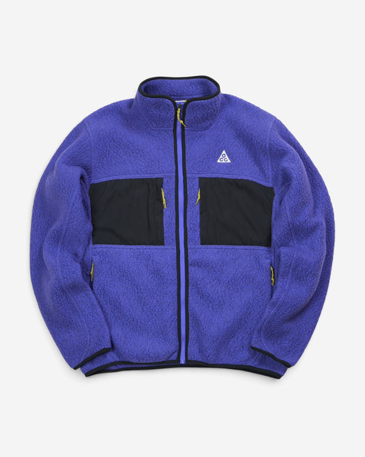 Фіолетова флісова куртка Nike ACG Arctic Wolf Full-Zip з високим коміром, чорними тканинними вставками на грудях та білим трикутним логотипом бренду.