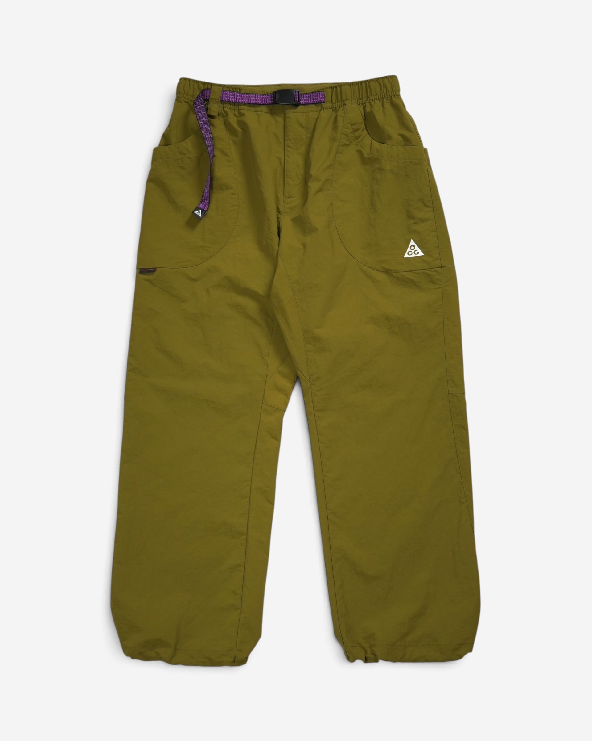 Оливкові вільні штани Nike ACG Dolomiti з еластичним поясом, фірмовим вбудованим фіолетовим ременем та білим трикутним логотипом бренду на лівій кишені.