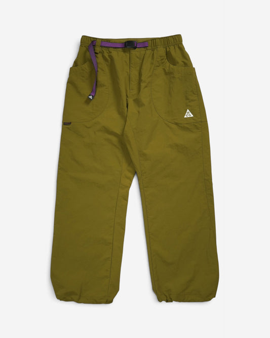 Оливкові вільні штани Nike ACG Dolomiti з еластичним поясом, фірмовим вбудованим фіолетовим ременем та білим трикутним логотипом бренду на лівій кишені.