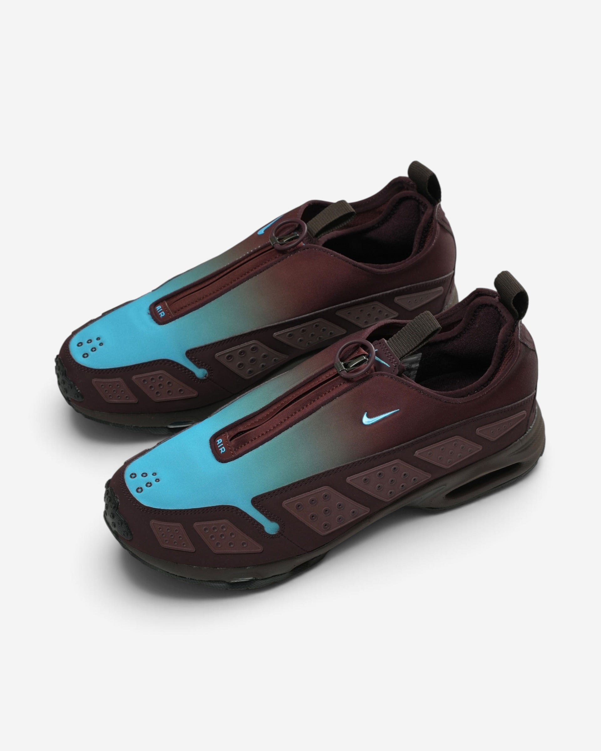Бордово-блакитні кросівки Nike Air Max SNDR з плавним градієнтом, застібкою-блискавкою по центру та маленьким блакитним логотипом бренду.