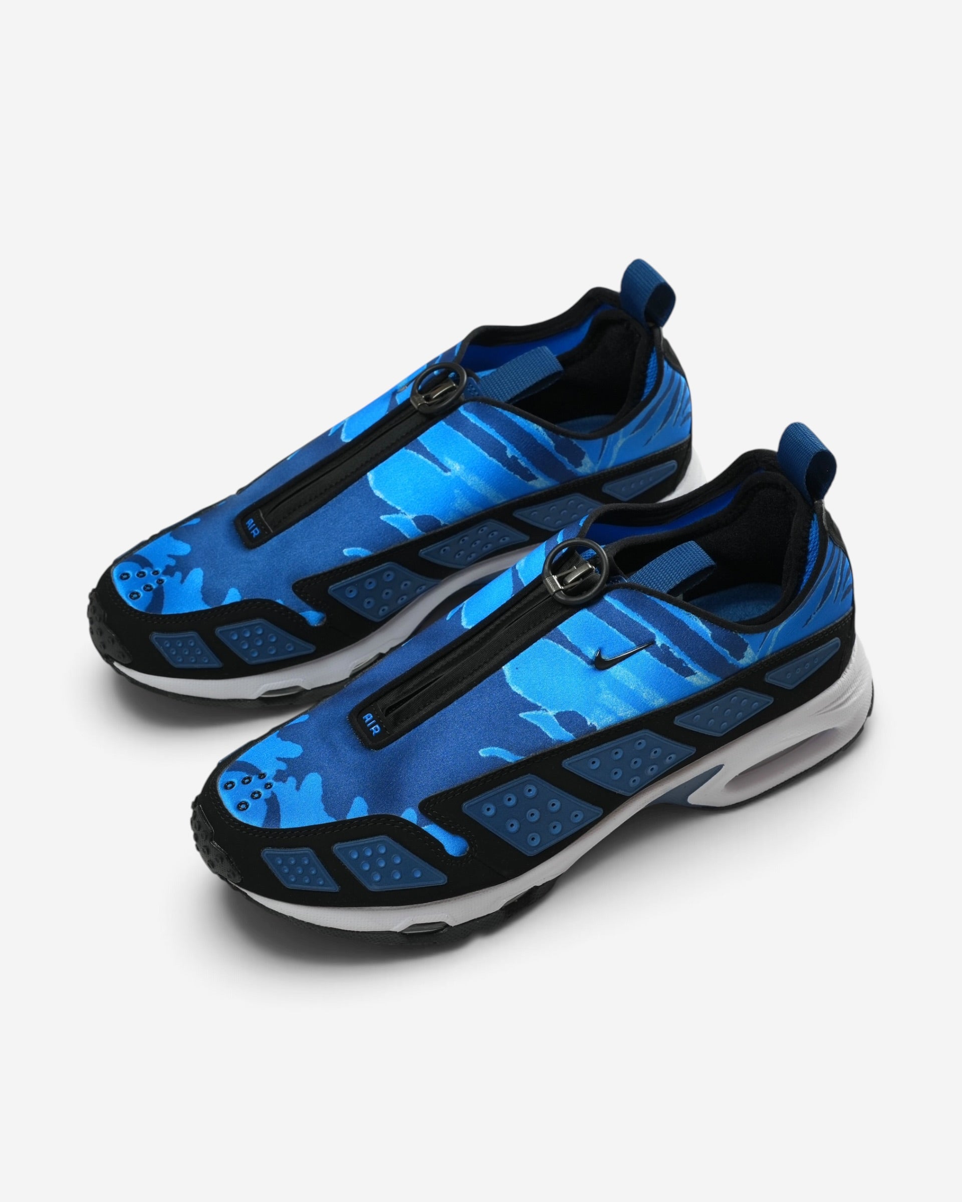 Сині чоловічі кросівки Nike Air Max SNDR з блакитним камуфляжним малюнком, чорною блискавкою по центру та чорними бічними панелями з отворами.