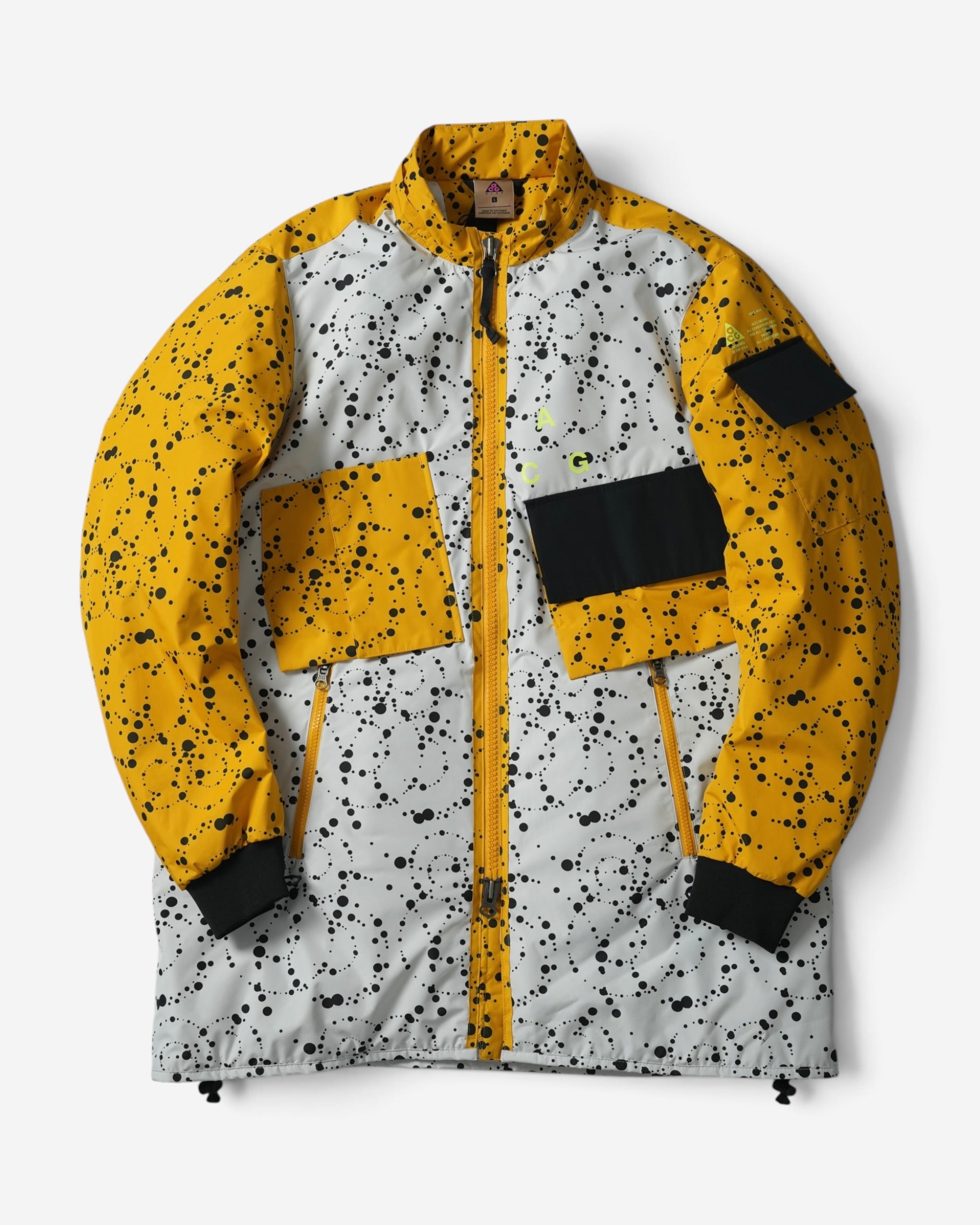 Чоловіча куртка NikeLab ACG біло-жовтого кольору з чорними бризками фарби, асиметричними кишенями на грудях та високим коміром без капюшона.