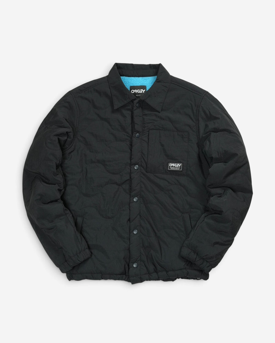 Стьобана куртка-сорочка Oakley Quilted Sherpa Jacket чорного кольору з відкладним коміром, кнопками та фірмовою нашивкою бренду на нагрудній кишені.