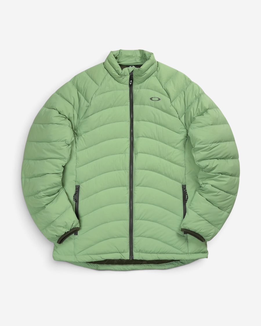 Пуховик Oakley Snowbound Packable Down Puffy Jacket світло-зеленого кольору New Jade з горизонтальним стьобанням, коміром-стійкою та логотипом на грудях.