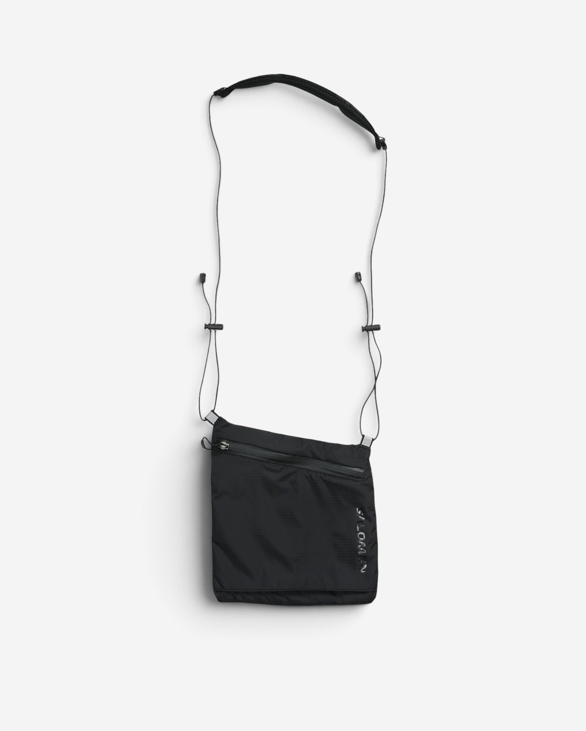 Чорна компактна сумка через плече Salomon ACS Pouch 2 з довгим тонким ремінцем і вертикальним написом бренду збоку.