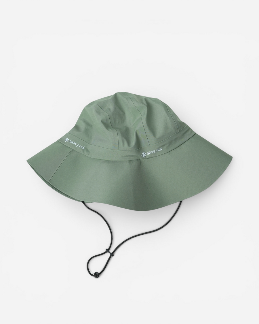 Світло-зелена аутдор-панама з широкими полями Snow Peak GORE-TEX Rain Hat із затяжкою-фіксатором на шнурку та світлими принтами брендів на тулії.
