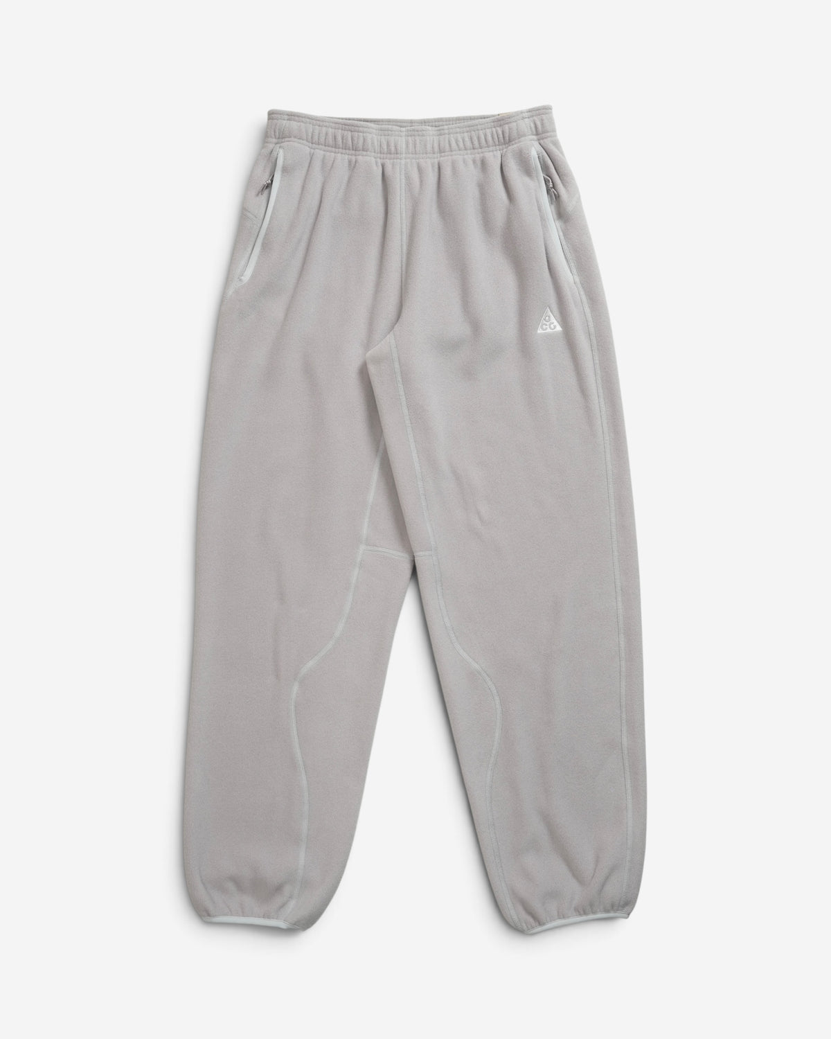 Жіночі сірі флісові штани Nike ACG Wolf Tree з вишитим білим логотипом на стегні та кишенями на блискавках.